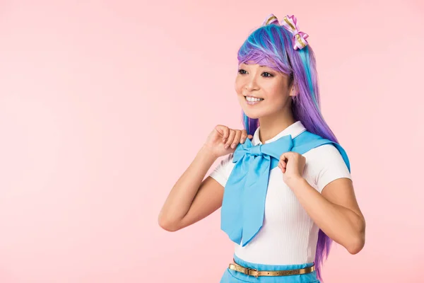 Sonriente chica otaku en peluca púrpura mirando hacia otro lado aislado en rosa - foto de stock