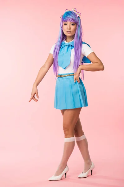 Vista completa de la bonita chica de anime en peluca y traje de marinero de pie en rosa - foto de stock
