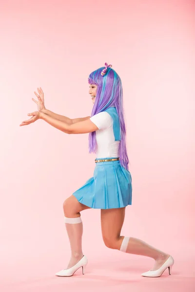 Pleine longueur vue de sourire otaku fille en perruque violette posant sur rose — Photo de stock