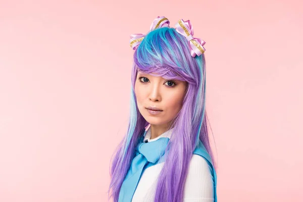 Hermosa asiático anime chica en morado peluca mirando cámara aislado en rosa - foto de stock