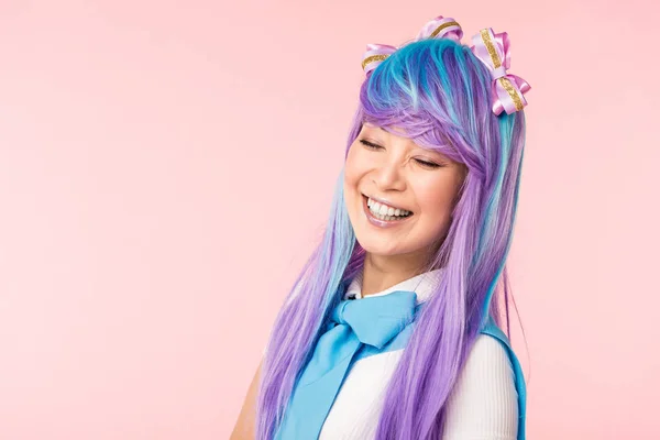Anime chica en peluca sonriendo con los ojos cerrados aislados en rosa - foto de stock