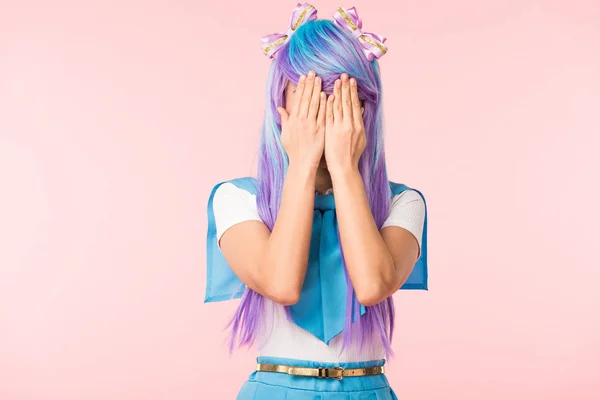 Anime chica en peluca cubriendo los ojos con las manos aisladas en rosa - foto de stock