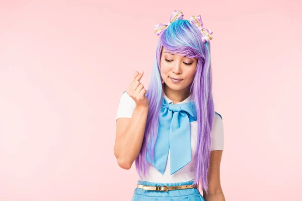 Anime chica en peluca mostrando el signo del corazón aislado en rosa - foto de stock