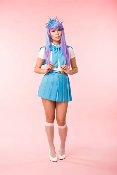Largura completa vista de triste asiático anime chica en falda de pie en rosa - foto de stock