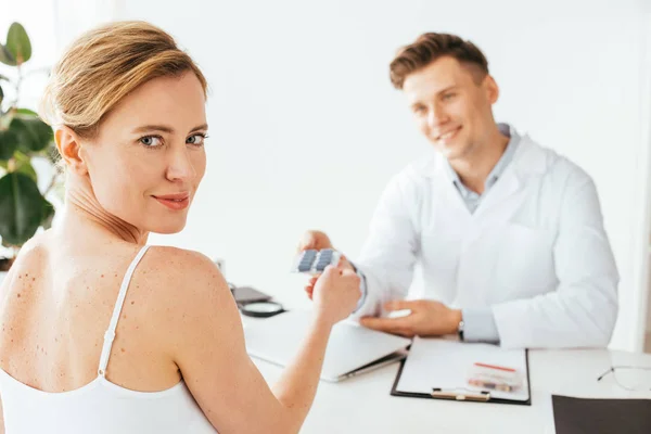 Selektiver Fokus attraktiver Frauen mit Pillen in der Nähe fröhlicher Ärztin — Stockfoto