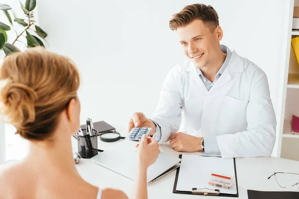 Selektiver Fokus der fröhlichen Ärztin, die der Frau Pillen verabreicht — Stockfoto