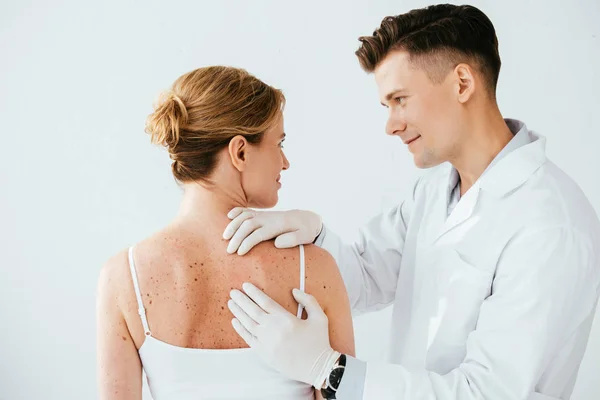 Schöner Dermatologe in Latexhandschuhen untersucht Frau mit Melanom isoliert auf weiß — Stockfoto