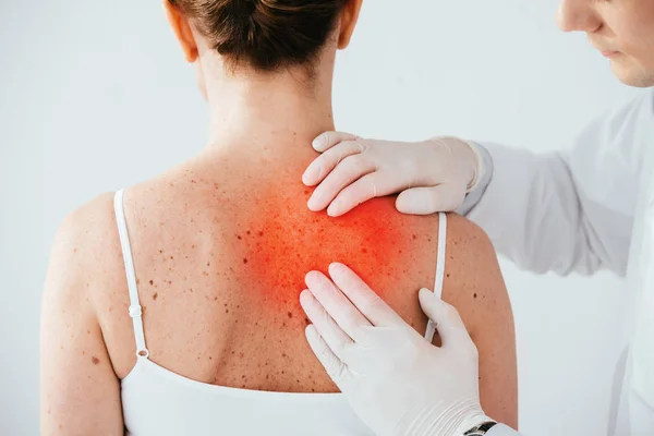 Vista recortada de dermatólogo en guantes de látex examinando mujer con melanoma aislado en blanco - foto de stock