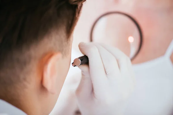 Vista cortada de dermatologista segurando lupa perto da mulher com melanoma — Fotografia de Stock