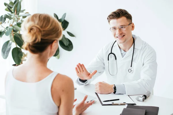 Selektive Fokussierung des gut gelaunten Arztes in Brille, der beim Anblick des Patienten gestikuliert — Stockfoto