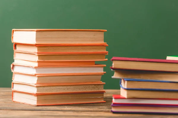 Colorful hardcover books on wooden surface isolated on green — Stock Photo