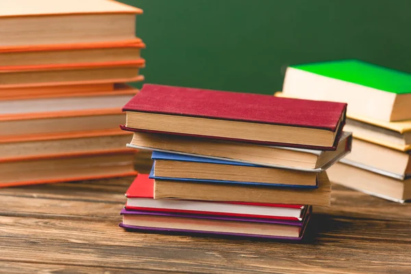 Livros de capa dura coloridos na superfície de madeira isolada em verde — Fotografia de Stock