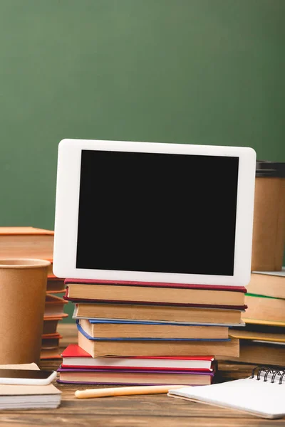 Books, notebooks, pen, disposable cups, smartphone and digital tablet with blank screen isolated on green — Stock Photo