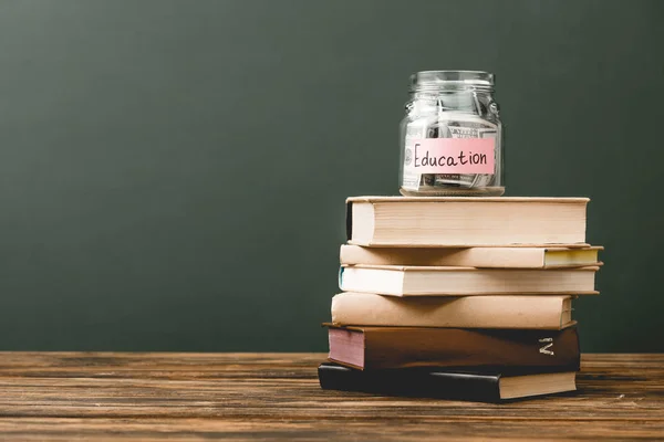 Stack of books and piggy bank on wooden surface isolated on grey — Stock Photo