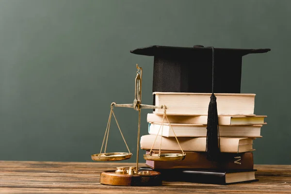 Books, academic cap and scales on wooden surface isolated on grey — Stock Photo