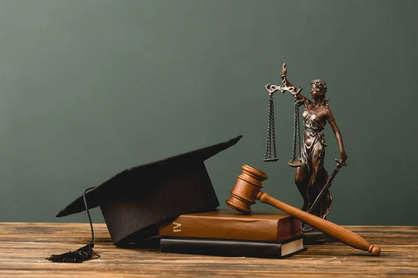 Livres, statuette thème, casquette académique et marteau sur surface en bois isolé sur gris — Photo de stock