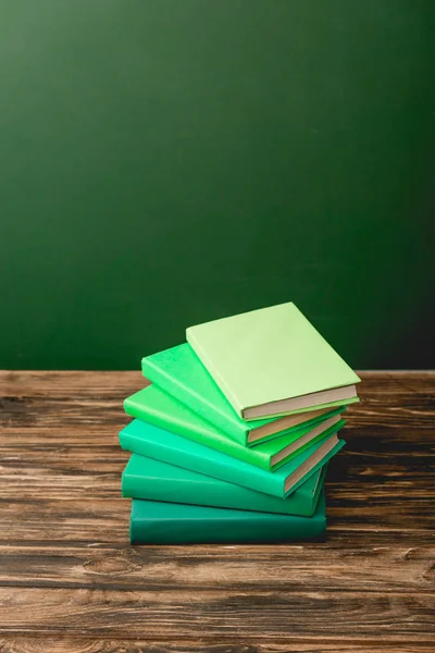 Pila di libri colorati su superficie di legno isolato su verde — Foto stock