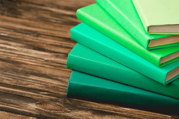 Stack of colorful books on wooden textured surface — Stock Photo