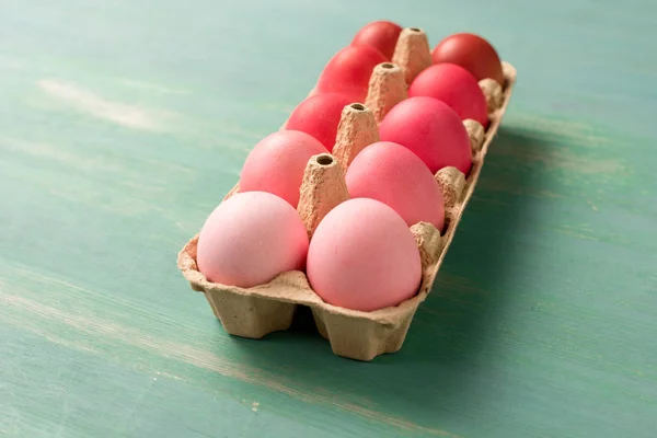 Painted easter eggs in cardboard carrier on textured surface — Stock Photo