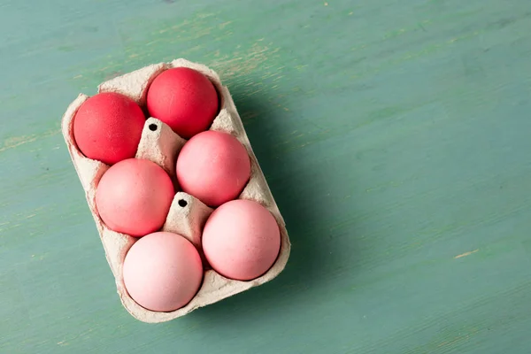 Верхний вид окрашенных пасхальных яиц в картонный носитель на текстурированной поверхности — стоковое фото