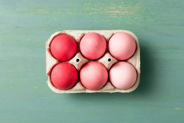 Vue du dessus des œufs de Pâques peints dans un support en carton sur une surface texturée — Photo de stock