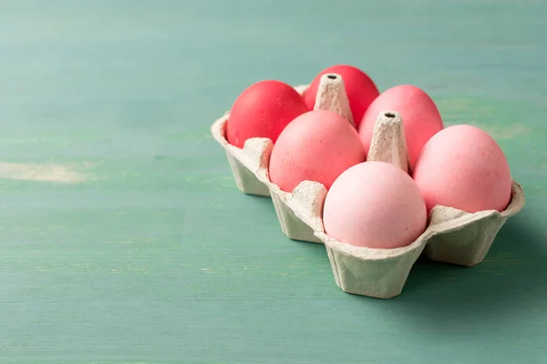 Painted easter eggs in cardboard carrier on textured surface — Stock Photo