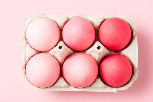 Top view of painted easter eggs in cardboard carrier on pink surface — Stock Photo