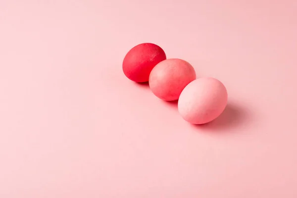 Три красочных окрашенных пасхальных яйца на розовой поверхности — стоковое фото