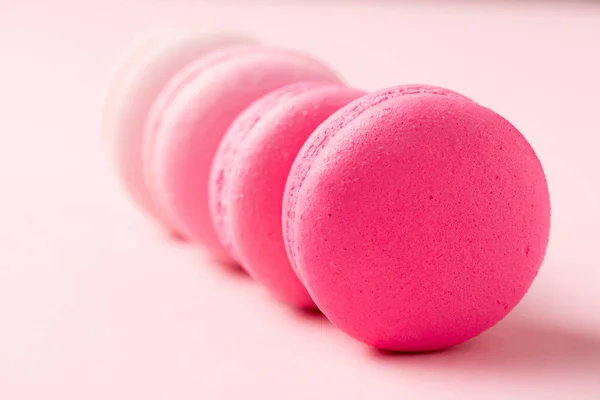 Messa a fuoco selettiva di dolci macaron colorati sulla superficie rosa — Foto stock