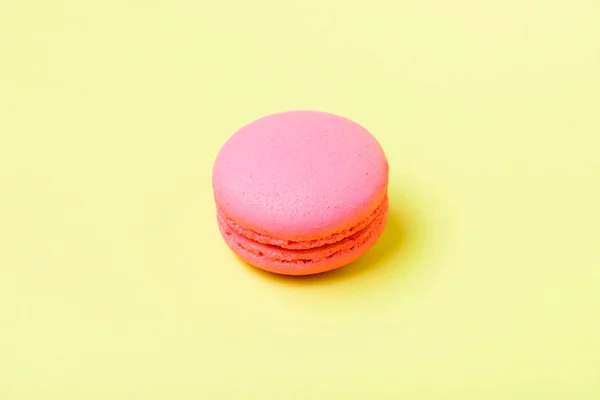 Pink macaron cookie with filling on yellow surface — Stock Photo