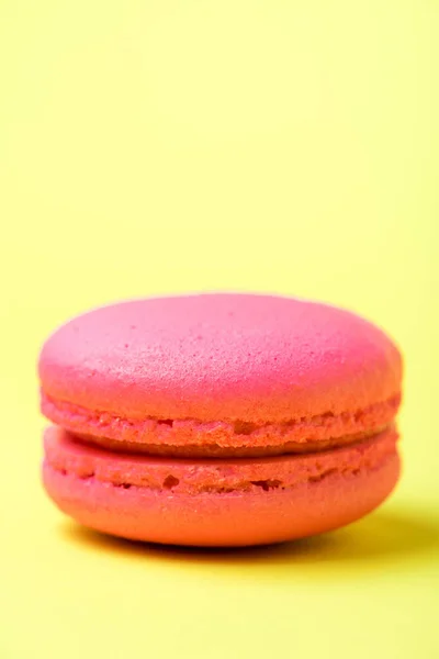 Pink macaron cookie with filling on yellow surface — Stock Photo
