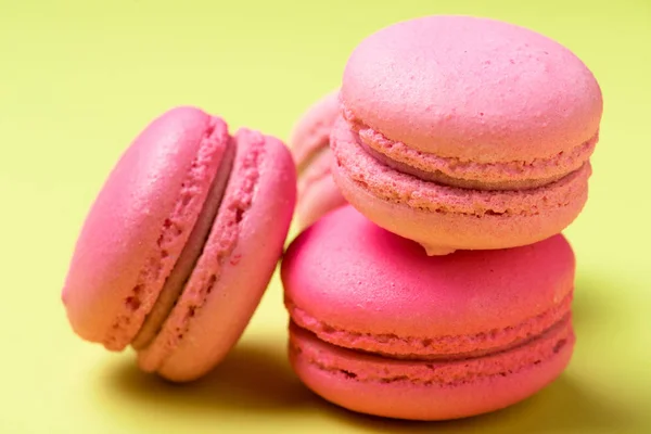 Tasty pink macarons with filling on yellow surface — Stock Photo