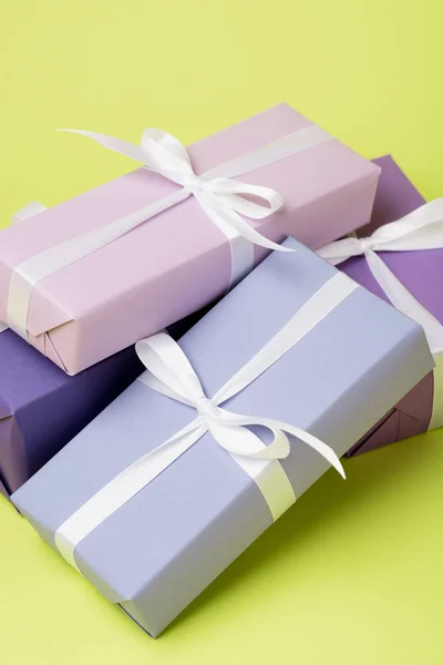 Purple gift boxes with white ribbons on yellow surface — Stock Photo