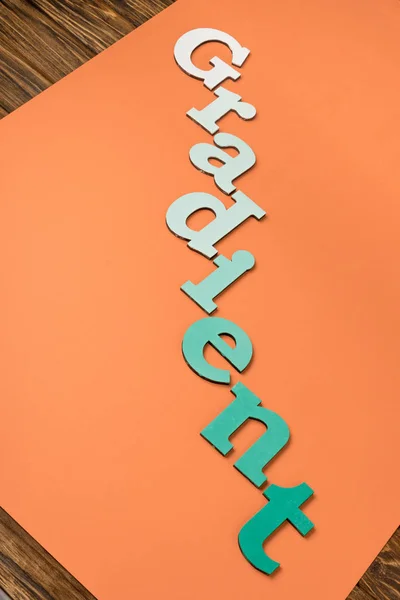 Palavra gradiente feita de letras verdes sobre papel laranja brilhante — Fotografia de Stock
