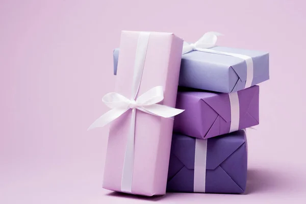 Colorful gift boxes with white ribbons on purple surface — Stock Photo