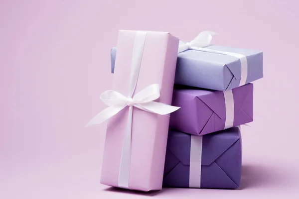 Boîtes-cadeaux colorées avec rubans blancs sur la surface violette — Photo de stock