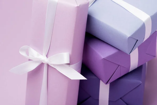 Colorful gift boxes with white ribbons on purple — Stock Photo