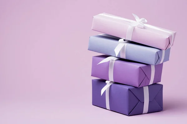 Colorful gift boxes with white ribbons on purple surface — Stock Photo