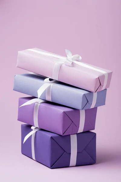 Colorful gift boxes with white ribbons on purple surface — Stock Photo