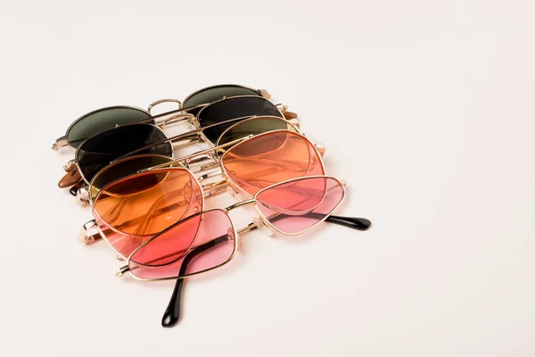 Stylish colorful sunglasses on white surface with copy space — Stock Photo