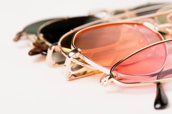 Selective focus of stylish colorful sunglasses on white surface — Stock Photo