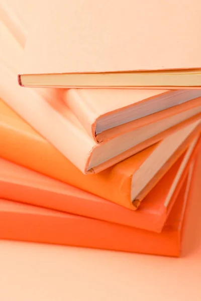 Pila de libros de tapa dura de colores en la superficie naranja - foto de stock