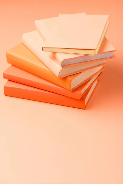 Stack of colorful hardcover books on orange surface — Stock Photo