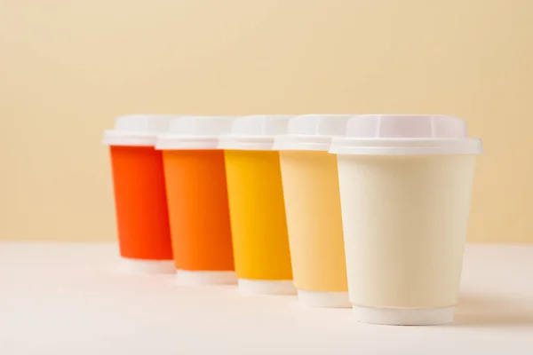 Selective focus of colorful disposable cups on white surface on beige — Stock Photo