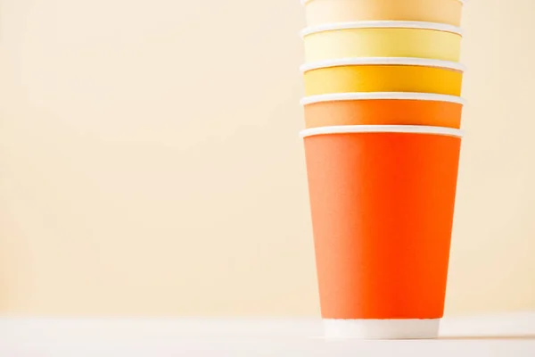 Красочные одноразовые чашки на белой поверхности, изолированные на бежевый — стоковое фото