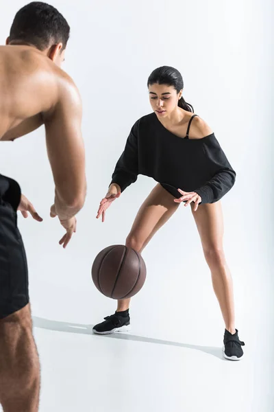 Attractive african american girl in black leotard playing ball with mixed race man on white — Stock Photo