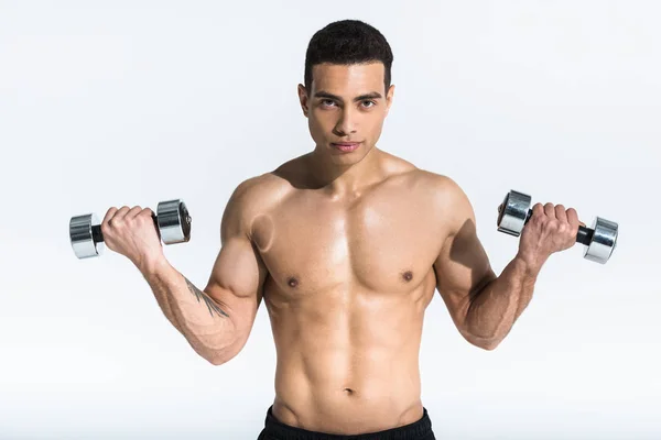 Handsome mixed race man holding dumbbells and looking at camera on white — Stock Photo
