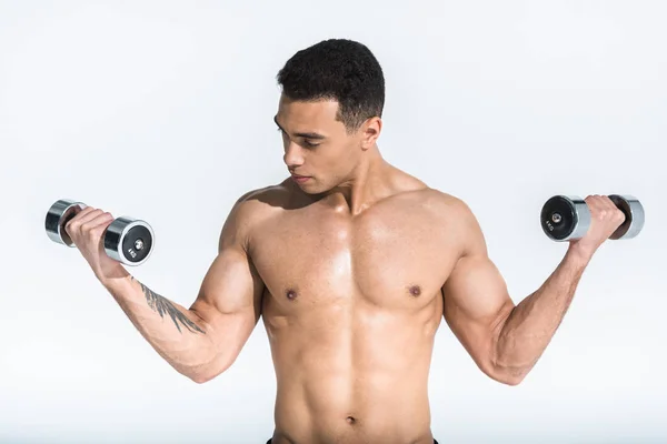 Hombre de raza mixta atlético atractivo con torso muscular celebración mancuernas en blanco - foto de stock