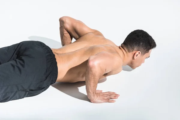 Atlético sin camisa mixta hombre haciendo flexiones en blanco - foto de stock