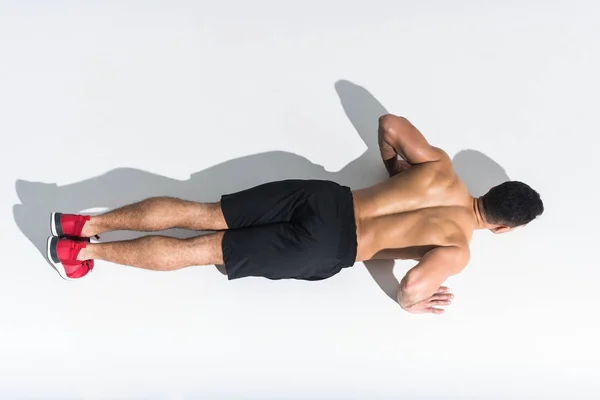 Overhead view of shirtless sportive man doing push ups on white — Stock Photo